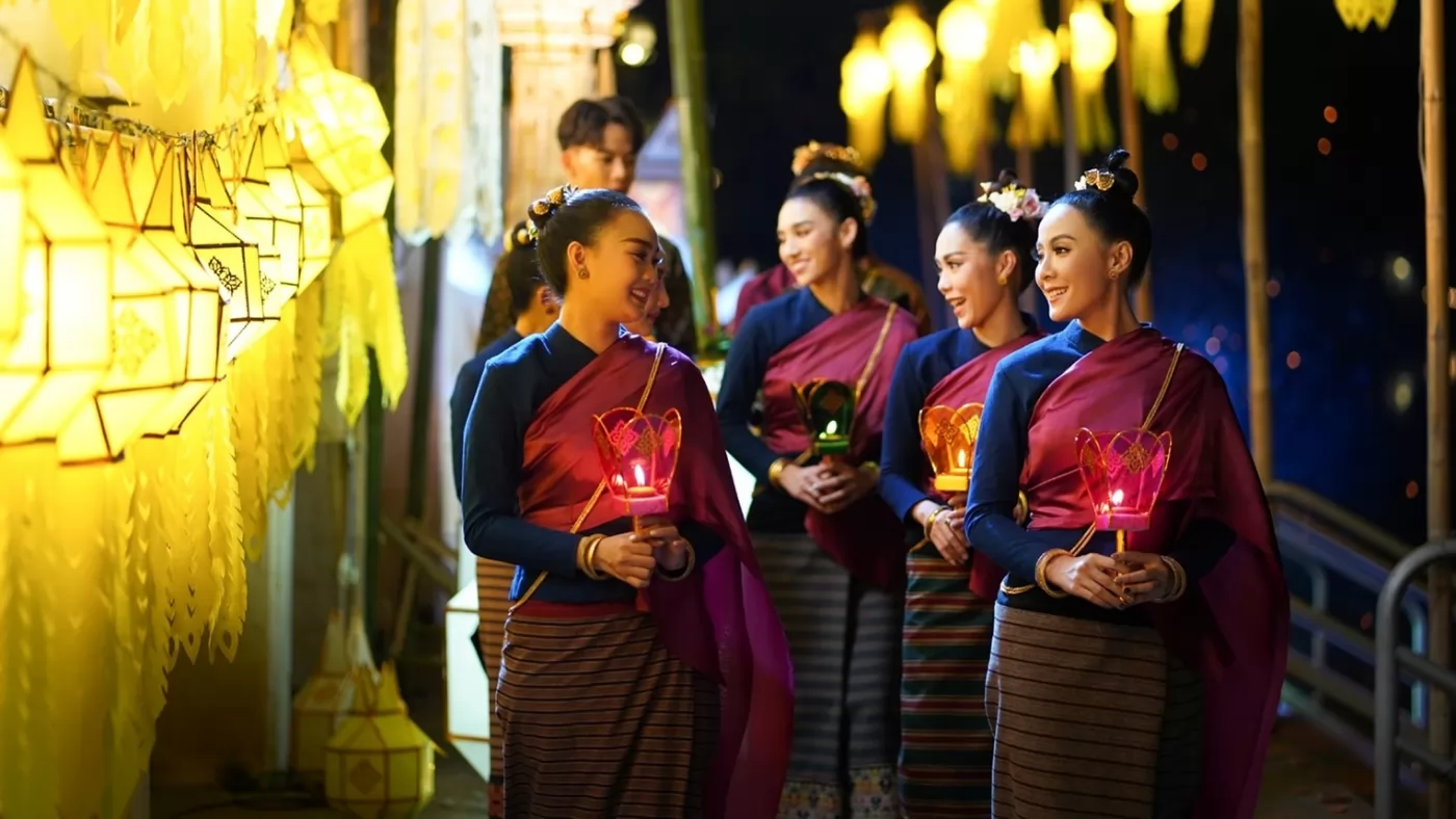 Beautiful women in northern Thai attire watching the water lanterns by the Ping River.